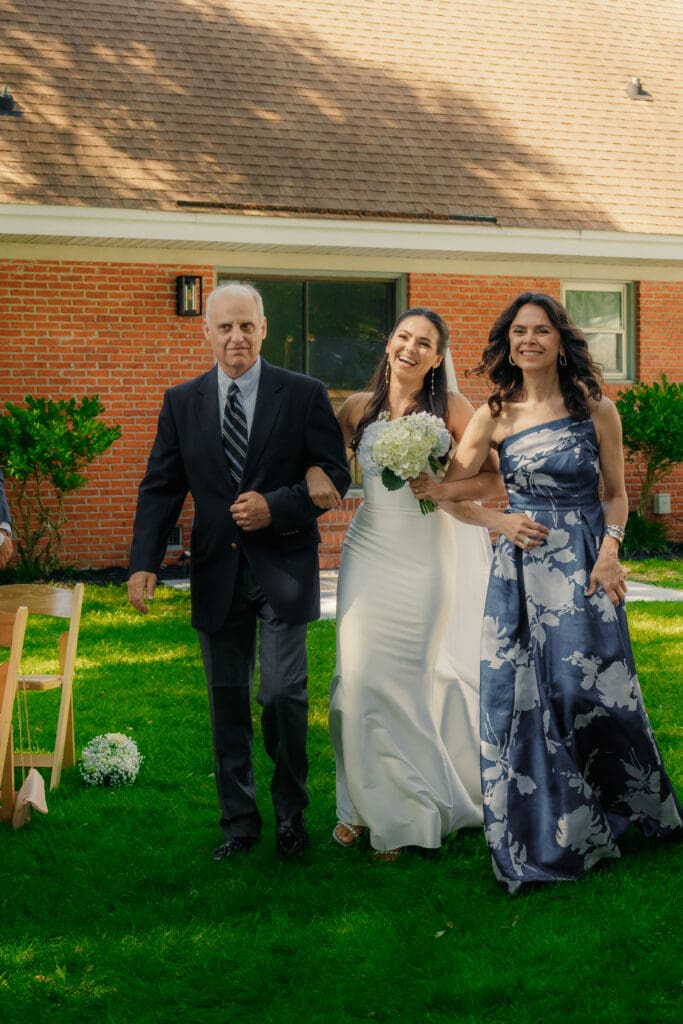Mother and Father walking their daughter down the aisle.