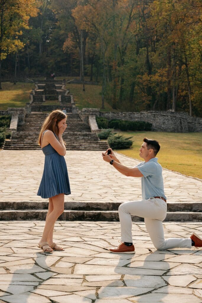 Groom-to-be kneeling during a surprise proposal at Percy Warner Park