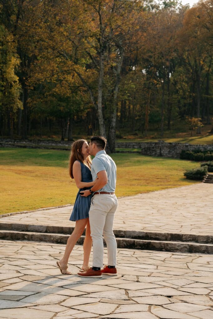 Couple sharing a kiss after saying yes during a proposal at Percy Warner Park